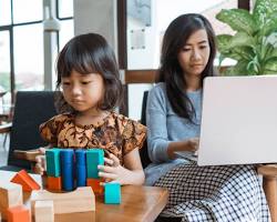 Hình ảnh về working parent studying at home with a child playing nearby